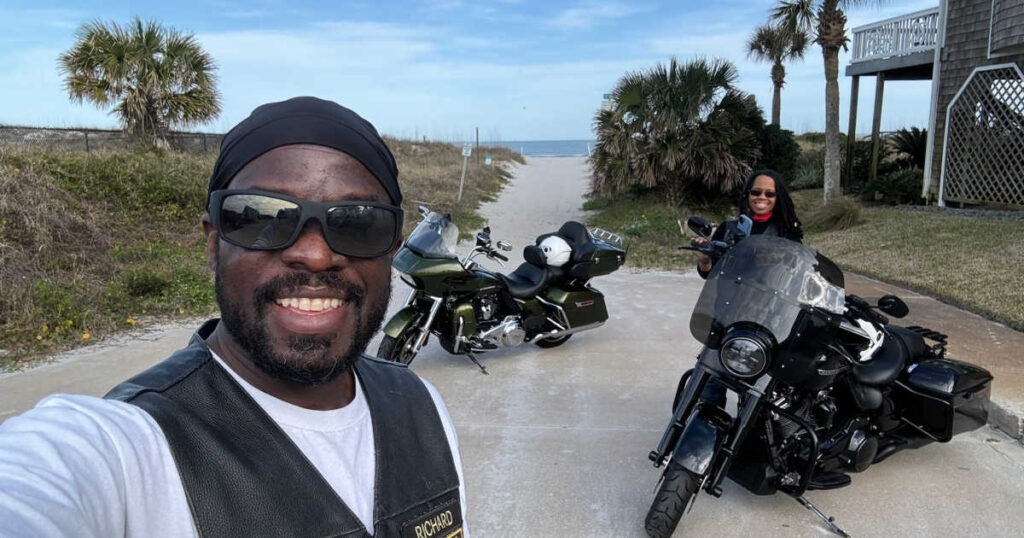 Man and woman by their Harley motorcycles in Florida near a beach.