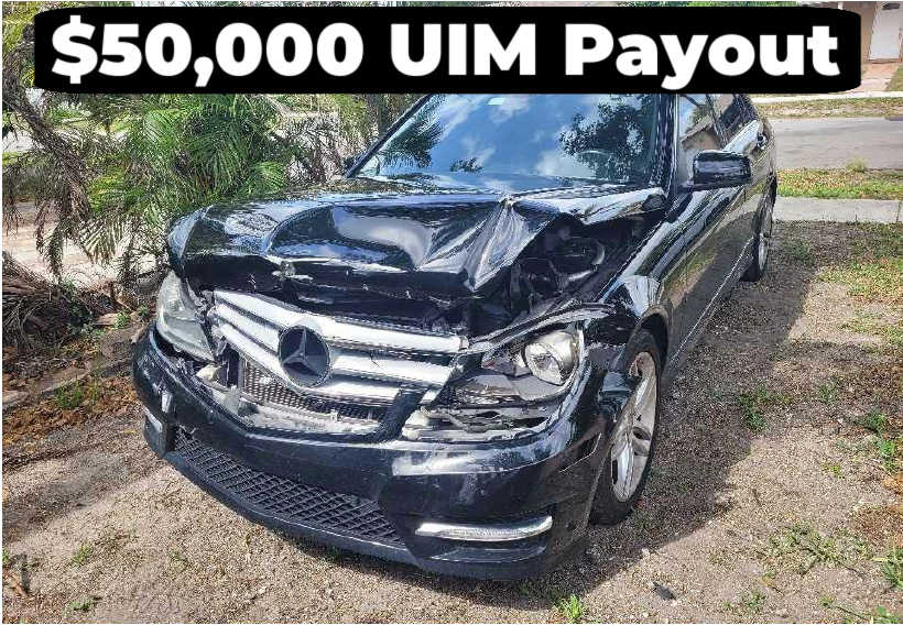 A damaged black Mercedes-Benz with a crumpled front end.  "$50,000 UIM Payout," highlighting an underinsured motorist insurance settlement.